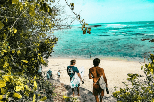 Travelers walking on the beach with surfboards