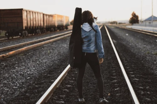 Best Travel Guitars - Girl walking on train tracks with a travel guitar